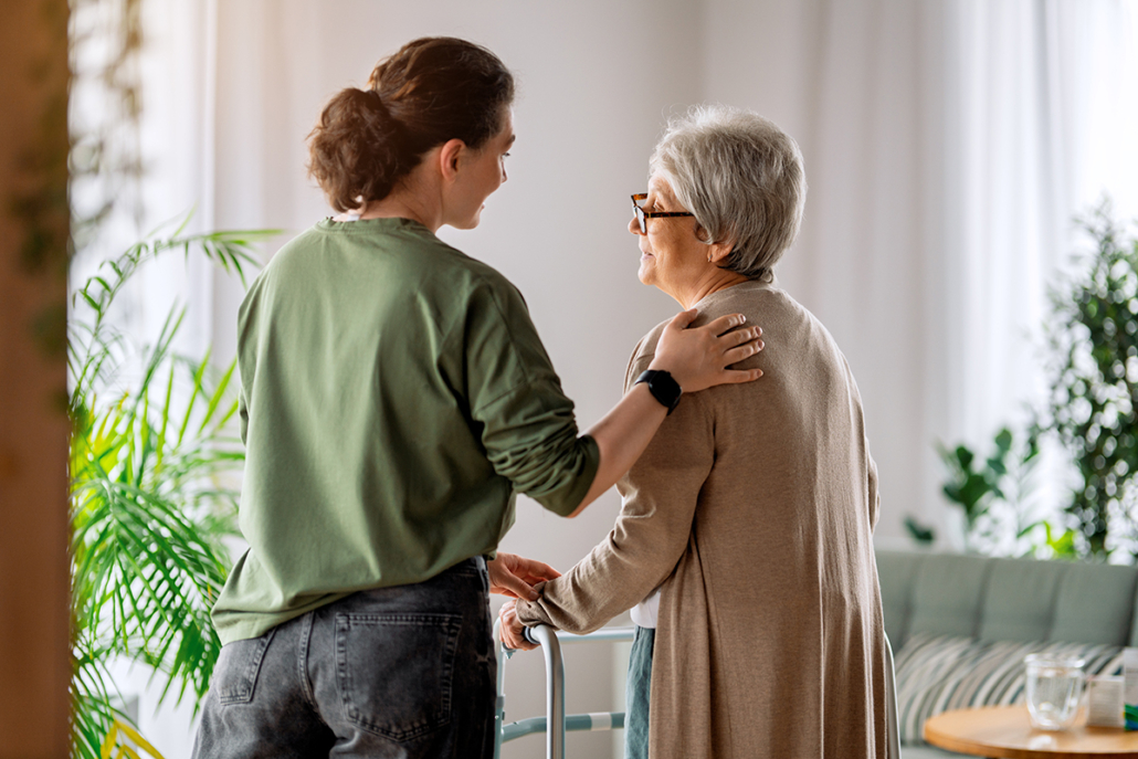 Young Caregiver Assisting Elderly Woman with Walker at Home in B